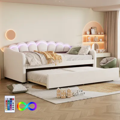 A bedroom setting with a daybed and trundle, decorated with soft lighting and accessories.
