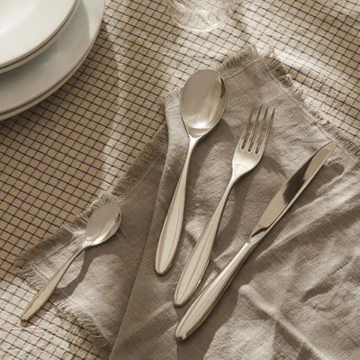 A set of cutlery is laid out on a checkered tablecloth and a grey napkin.