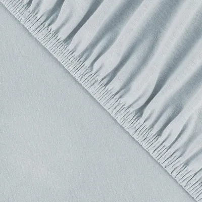 A close-up view of a light blue fitted sheet with elastic gathering along the edge.
