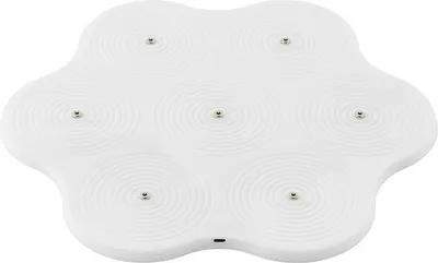 A white, flower-shaped wireless charging pad with multiple circular indentations, each containing a small metallic pin.