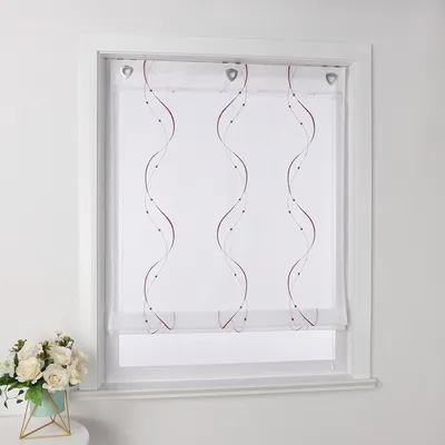 A white sheer roller blind with embroidered purple wavy lines and dots is shown hanging in a window frame. A small bouquet of white flowers in a teal pot sits on a surface to the left.