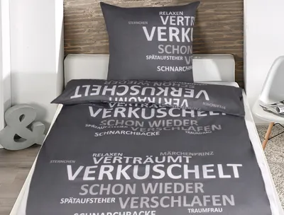 A bed with a duvet cover and pillowcase featuring a word cloud design.