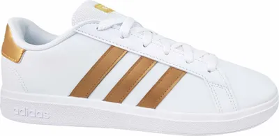 A white Adidas sneaker with gold stripes and accents, shown from the side.