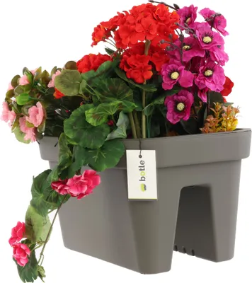 A gray planter box filled with artificial flowers, with a tag attached.