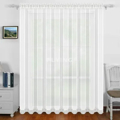 A white sheer curtain with vertical stripes and lace trim at the bottom, hanging in front of a window. A small framed picture is on the wall to the left, and a white chair is to the right.