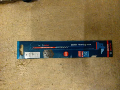 A Bosch EXPERT saw blade in its packaging, lying on a wooden surface.