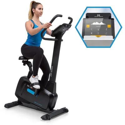 A woman is using an exercise bike, with a close-up inset showing the bike's console display.