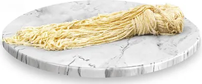 A bundle of yellow noodles is placed on a round marble-like surface.