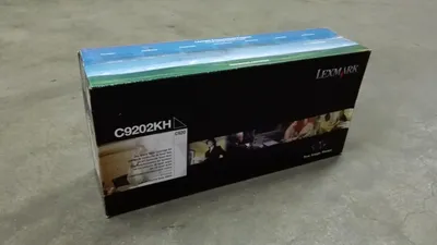 A product box for a Lexmark toner cartridge is placed on a concrete floor.