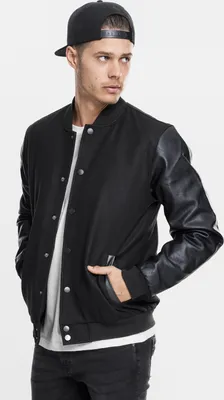 A man wearing a black college jacket and a black baseball cap, posing against a white background.