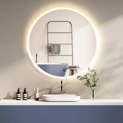 A modern bathroom vanity with a round, illuminated mirror above a sink and faucet. A blue bathtub and a towel rack are visible in the reflection.