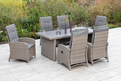 An outdoor dining set on a patio with greenery in the background.