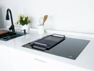 A modern kitchen countertop with a sink and a black induction cooktop.