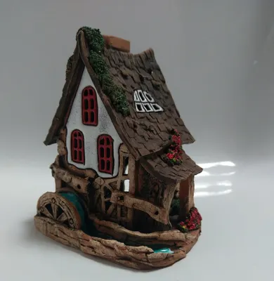 Eine detaillierte Darstellung einer kleinen Keramikwassermühle. Braunes Dach mit weißen Wänden.