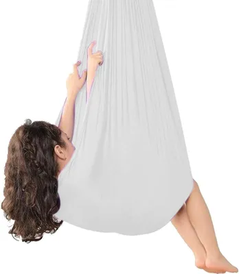 A child is lying in a white fabric swing.