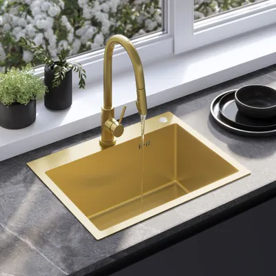 A gold sink and faucet are shown in a kitchen setting with plants and dishes.