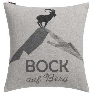 A pillow with a graphic design of a goat on a mountain and text.