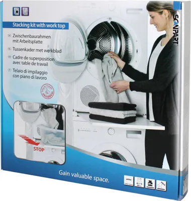 A woman is loading laundry into a dryer, which is stacked on top of a washing machine, with a stacking kit that includes a worktop.