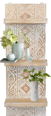 A wooden wall shelf with decorative carvings and three shelves, adorned with vases of flowers and a potted plant.