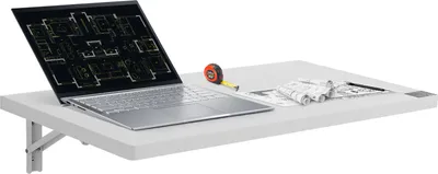 A white wall-mounted folding table with a laptop displaying blueprints, a tape measure, and rolled-up papers on it.