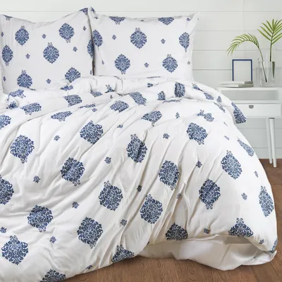 A neatly made bed with white bedding featuring a blue ornamental pattern.