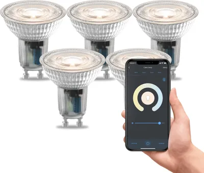 A hand holding a smartphone displaying a smart lighting app, with a set of smart LED spotlights in the background.