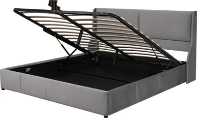 A grey upholstered bed frame with the mattress support mechanism lifted to reveal the storage space underneath.