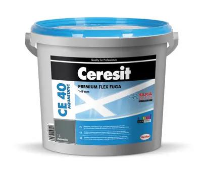 A gray plastic bucket with a blue lid, containing grout. The label on the bucket shows product information and branding.