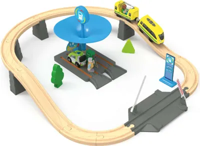 A toy train set with a gas station, cars, and trains on a wooden track.
