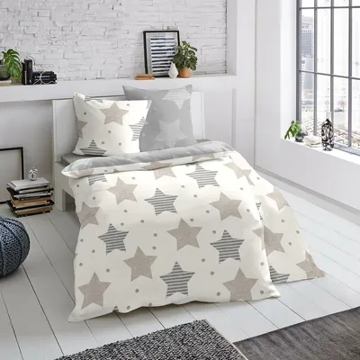 A bedroom scene with bedding on a bed, next to a window.