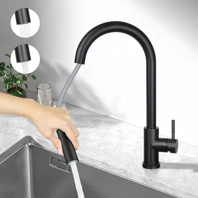 A person is using a black kitchen faucet with a pull-down sprayer in a modern kitchen sink.