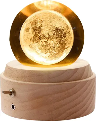 A close-up shot of a moon-shaped music box with a wooden base, illuminated from within.