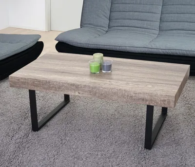 A coffee table in a living room setting with a sofa and floor cushions.