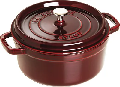 A red Staub cocotte pot with a silver handle on a white background.
