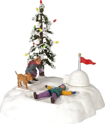 A miniature Christmas village scene with a decorated tree, an igloo, and figures playing in the snow.