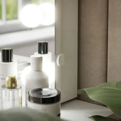 Cosmetic products arranged on a shelf in front of a mirror with lights.