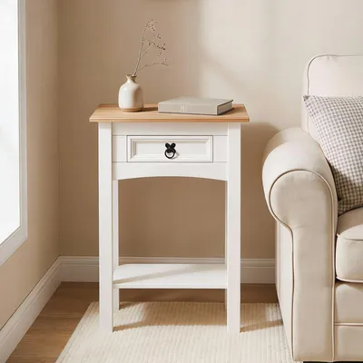 A small white and brown console table with one drawer and a shelf, placed next to a cream-colored sofa.