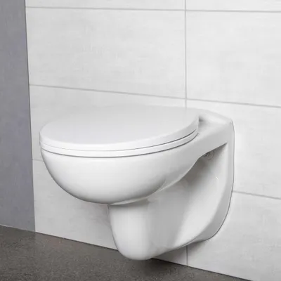 A white wall-mounted toilet against a tiled wall.