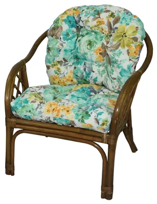 A rattan armchair with floral cushions.