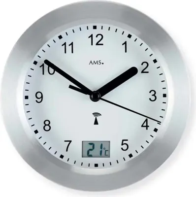 A close-up view of a silver wall clock with a white face, black hands, and a digital display showing the temperature.