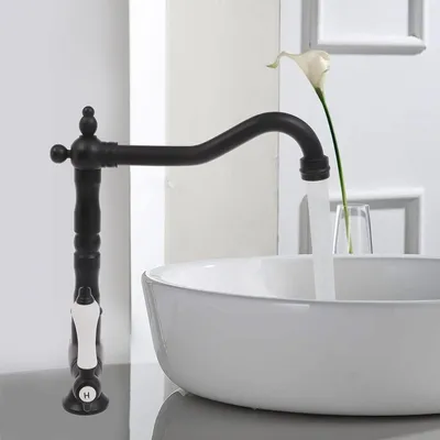 A black retro-style faucet is shown above a white sink, with water running from the faucet.