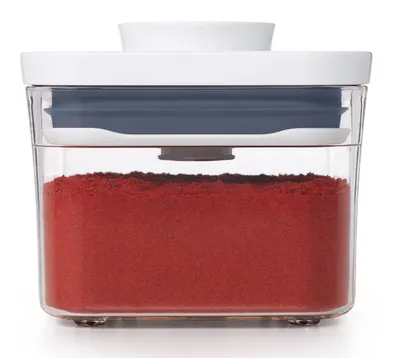 A clear, front-facing studio shot of a food storage container filled with red powder.