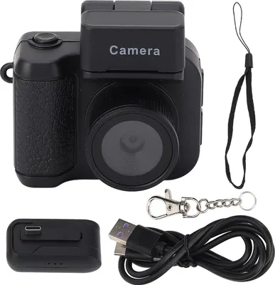 A black digital camera with accessories laid out on a white background.