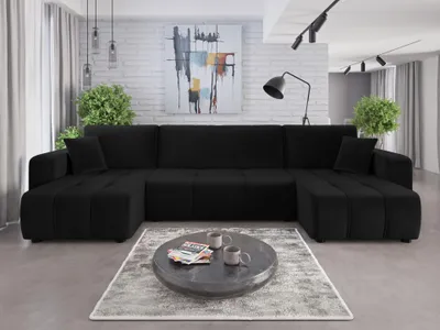 A black U-shaped sofa in a modern living room with a painting on the wall and a coffee table in front.