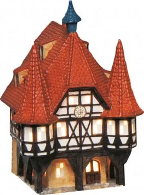 A miniature, illuminated building resembling a town hall or similar structure, with a red tiled roof and half-timbered facade.