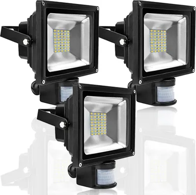 Three black LED floodlights with motion sensors are arranged in a cluster on a white background.