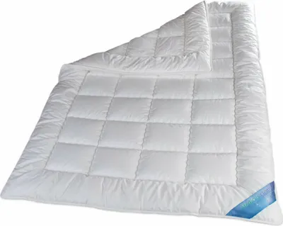 A white quilted duvet is laid out on a white background.