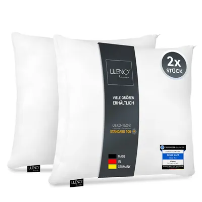 Two white pillows are shown, one slightly behind the other, with a product label on the front of the right pillow.