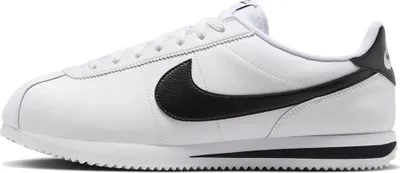 A side view of a white Nike Cortez sneaker with a black Nike swoosh and black heel accent.
