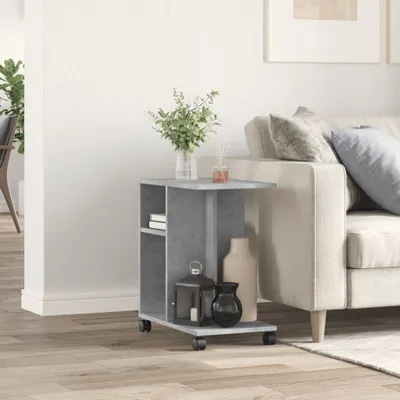 A small grey side table with shelves and wheels is placed next to a sofa in a living room. Decorative items like vases and a lantern are on the table.